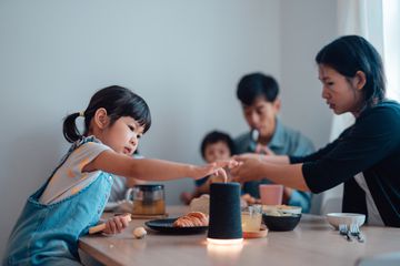 A child presses an Amazon Echo at the family dinner table