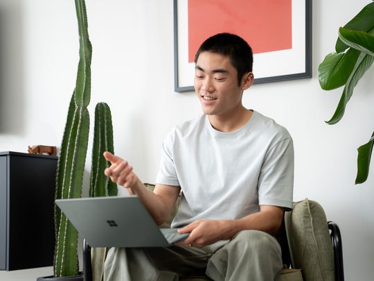 A young man looking frustrated with a Microsoft Surface Pro Windows 11 computer on his lap.