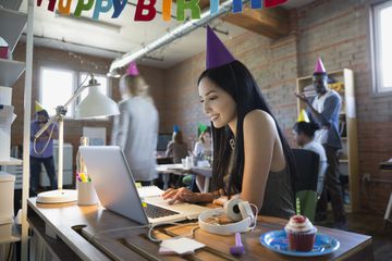 Businesswoman wearing birthday party hat at laptop