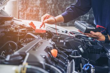 A car mechanic diagnosing a car engine.