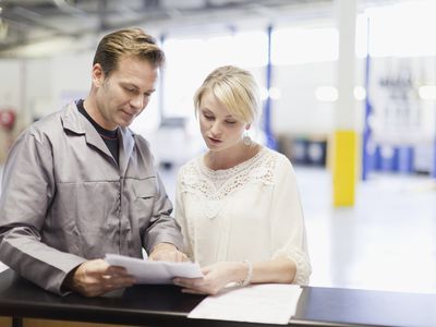 A technician helps a woman look up her car radio code.