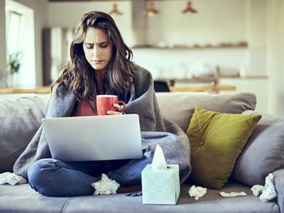 Woman on couch with used tissues around her