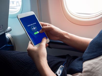 A person enabling Airplan Mode on their smartphone on a plane.