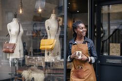 A small business owner stands outside her handbag shop.