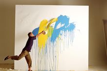 Artist throwing paint at canvas