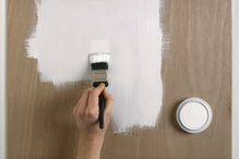 Applying a coat of gesso primer on wooden surface, close-up