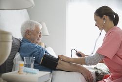 Home care nurse taking senior mans blood pressure