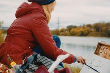 Side View Of Woman Painting While Sitting At Lakeshore