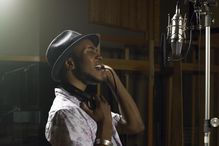 Young man singing into a mic in a studio