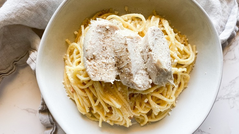 A bowl filled with carbonara topped with chicken.