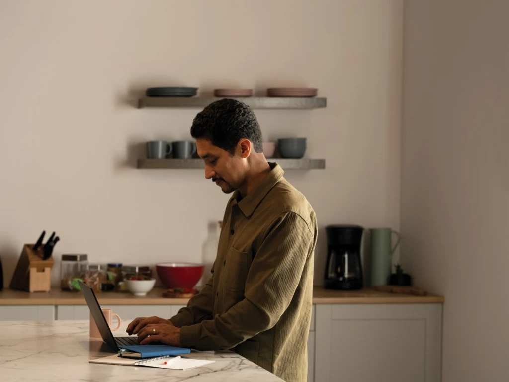 A man working from the kitchen during the day with a Lenovo ThinkPad X1 Yoga. Keywords: remote work, remote working, work from home, working at home, home office