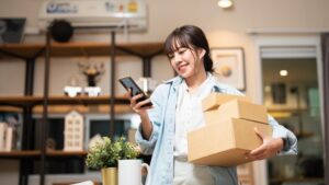 woman shopping while holding packages and looking at her device.