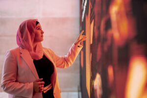 Young woman standing and using a big digital touch screen.