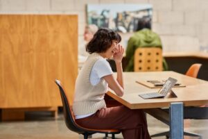 A woman participating in a Microsoft Teams meeting on a Surface device while hotdesking in an open work space​.