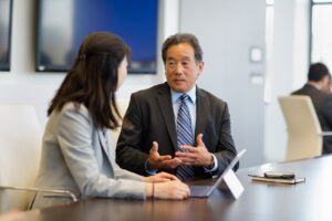 Two executives in a discussion in a conference room. Business attire.