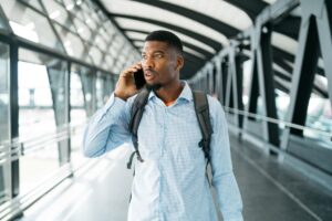 A young man walks through an airport talking on the phone.