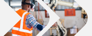 Adult male wearing orange safety vest works in mechanical shop.