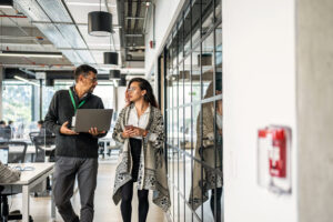 Coworkers discuss business while walking through a modern office