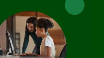 A man and a woman looking at a computer screen with a decorative, green frame around the image.