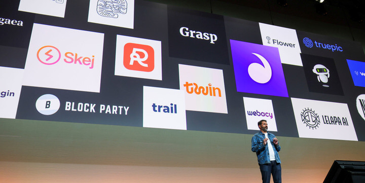 Speaker on stage with multiple product logos.