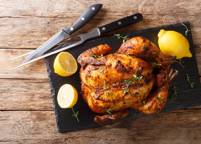 Whole rotisserie chicken on a cutting board.