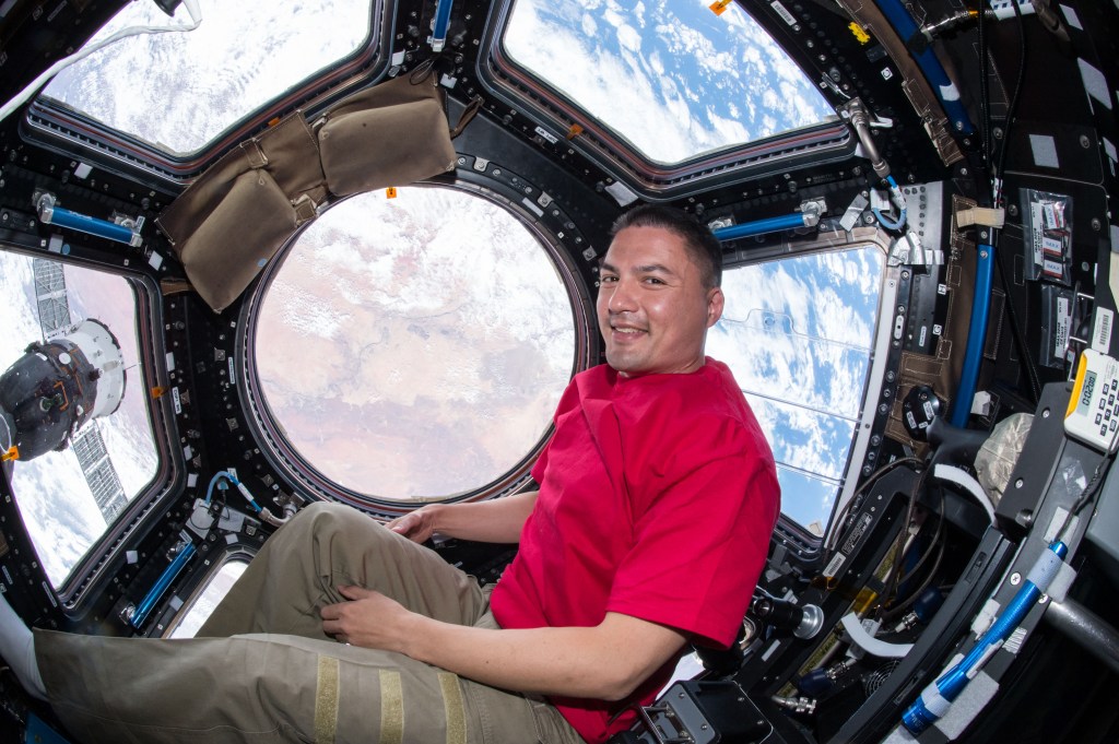 View of NASA astronaut Kjell Lindgren floating in front of the Cupola window.