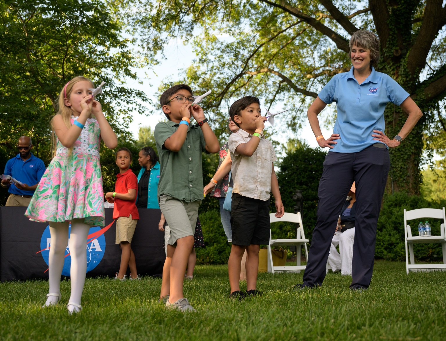 Helping student’s summer slide With NASA STEM. Three young students, a girl and two boys, having fun while they blow into straws to launch their soda-straw rockets. 