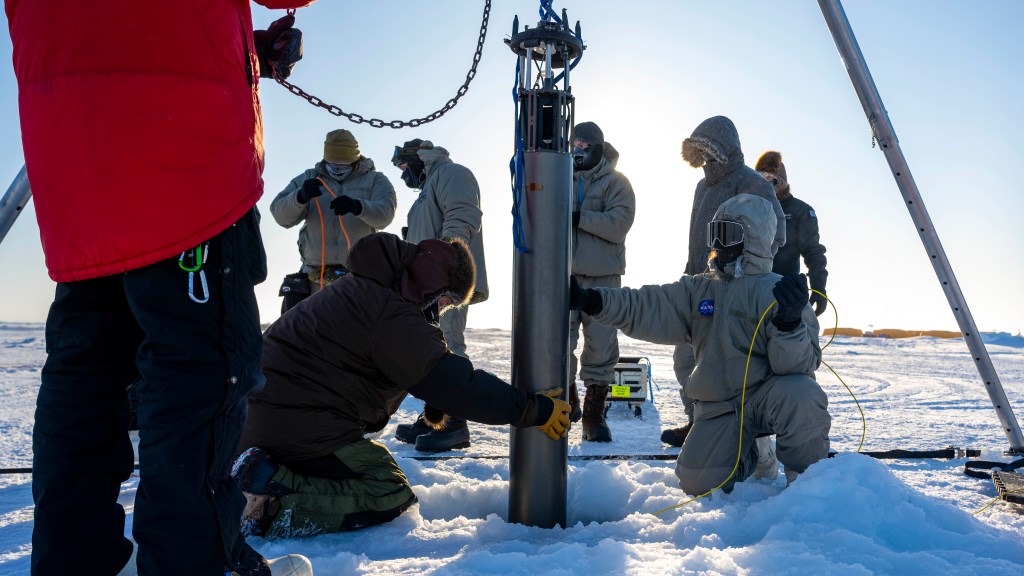 A prototype of a robot built to access underwater areas where Antarctic ice shelves meet land is lowered through the ice during a field test north of Alaska in March.