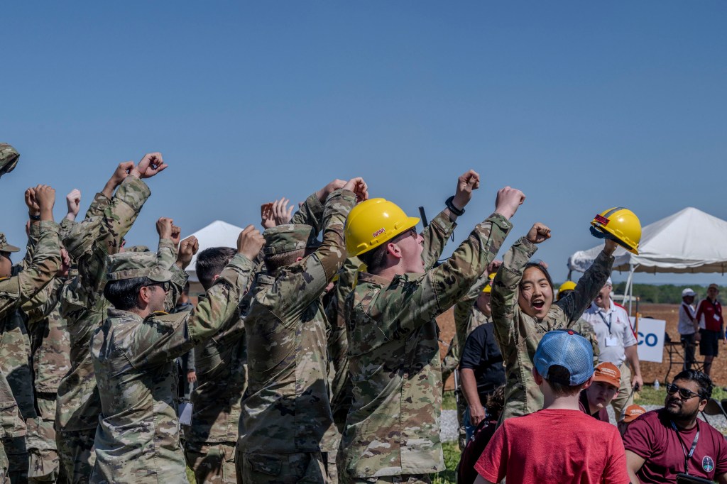 Students raise their hands in celebration and cheer after a successful launch of their vehicle in the 2024 Student Launch competition.