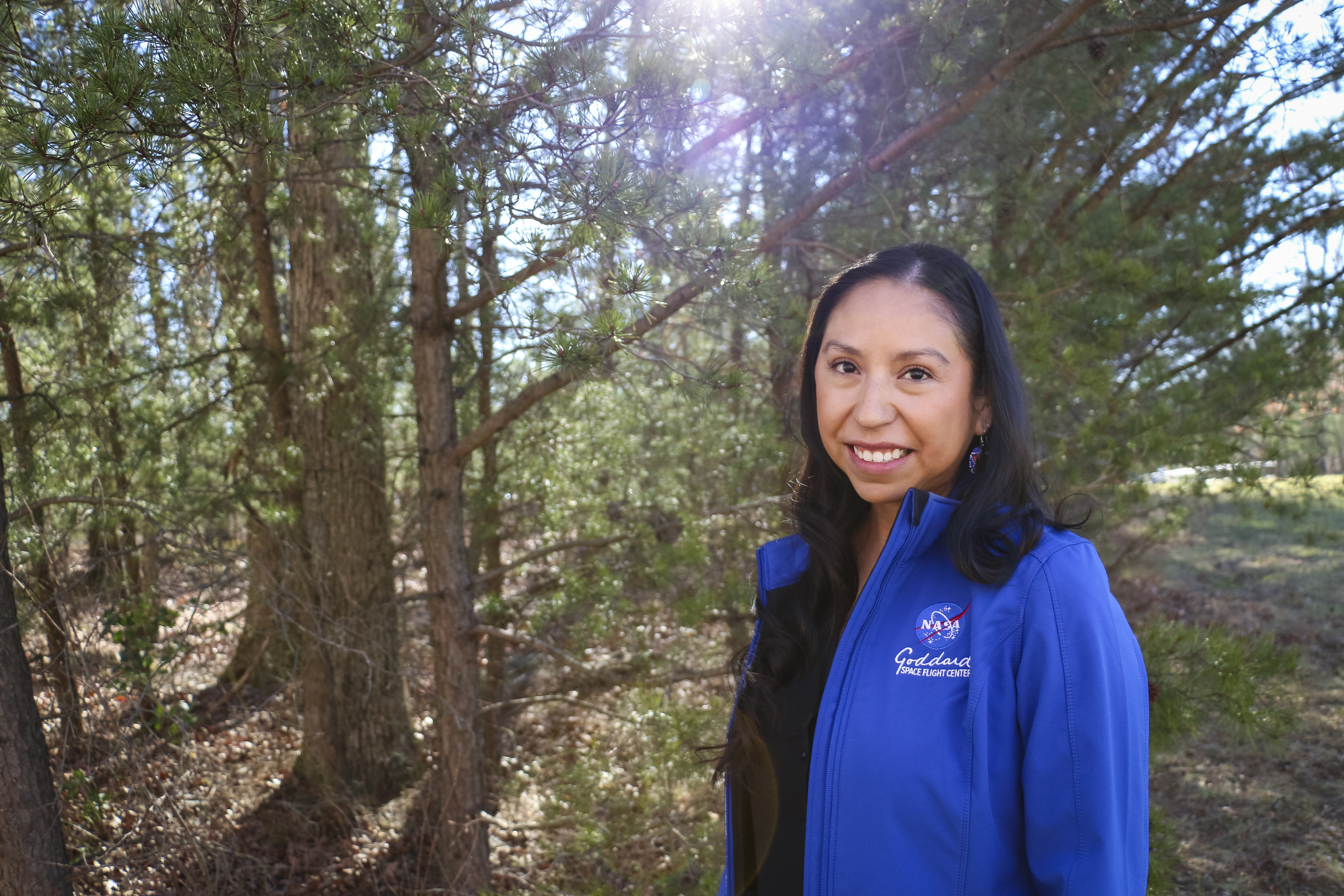 Miranda Meyer, a Native American woman, poses for a portrait amid trees.