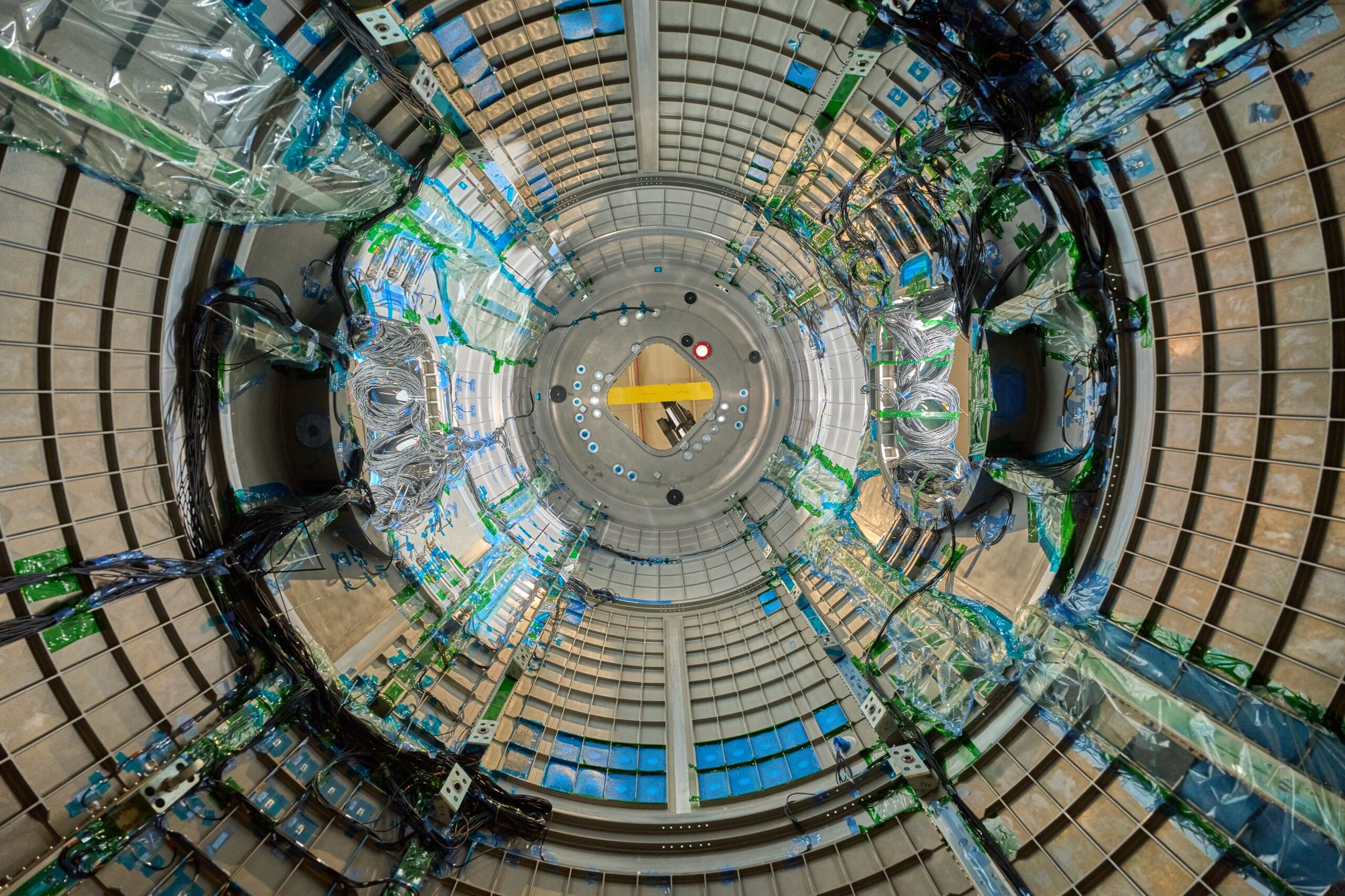 As we look through a circular piece of Gateway, a space station that will be in lunar orbit, there are blue wires snaking through. The wires are covered in clear plastic in some places and held onto the walls by green tape in others.