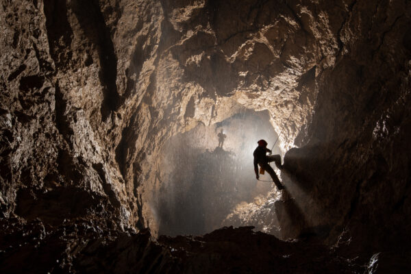 Two of the Russian explorers begin their journey into the lowest levels of the cave. This is a view from close to the lowest camp at -1900m below ground and where the rope comes in from the surface, 1900m above. This is also the shaft from where all the flood water plummeted a week after this photograph was taken. Here, it is in pretty much normal conditions. When the flood pulse came, all this space was wall to wall white water. It was terrifying and extremely loud.