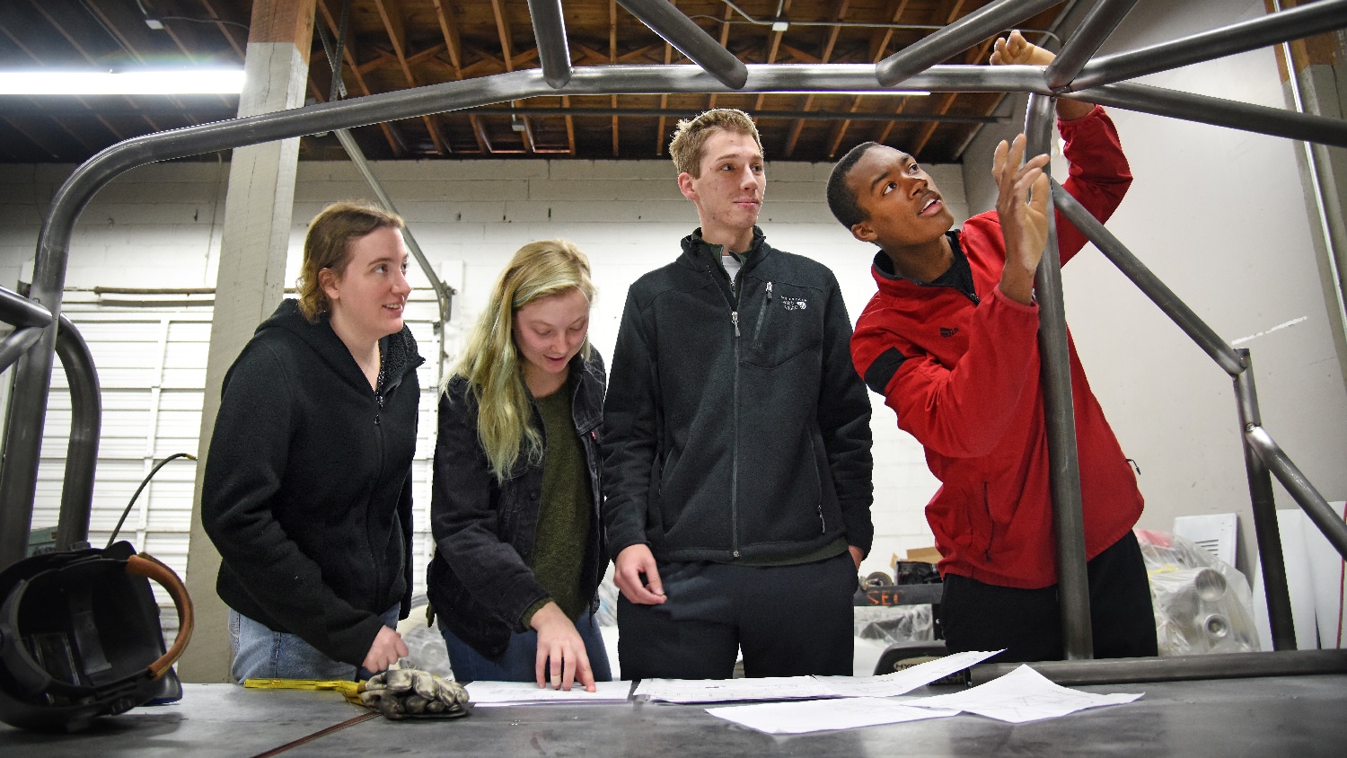 Mechanical engineering's Bryon Spells (right) points out recent welding work to SolarPack teammates while checking on the progress of their car at Eastern Rod and Customs.