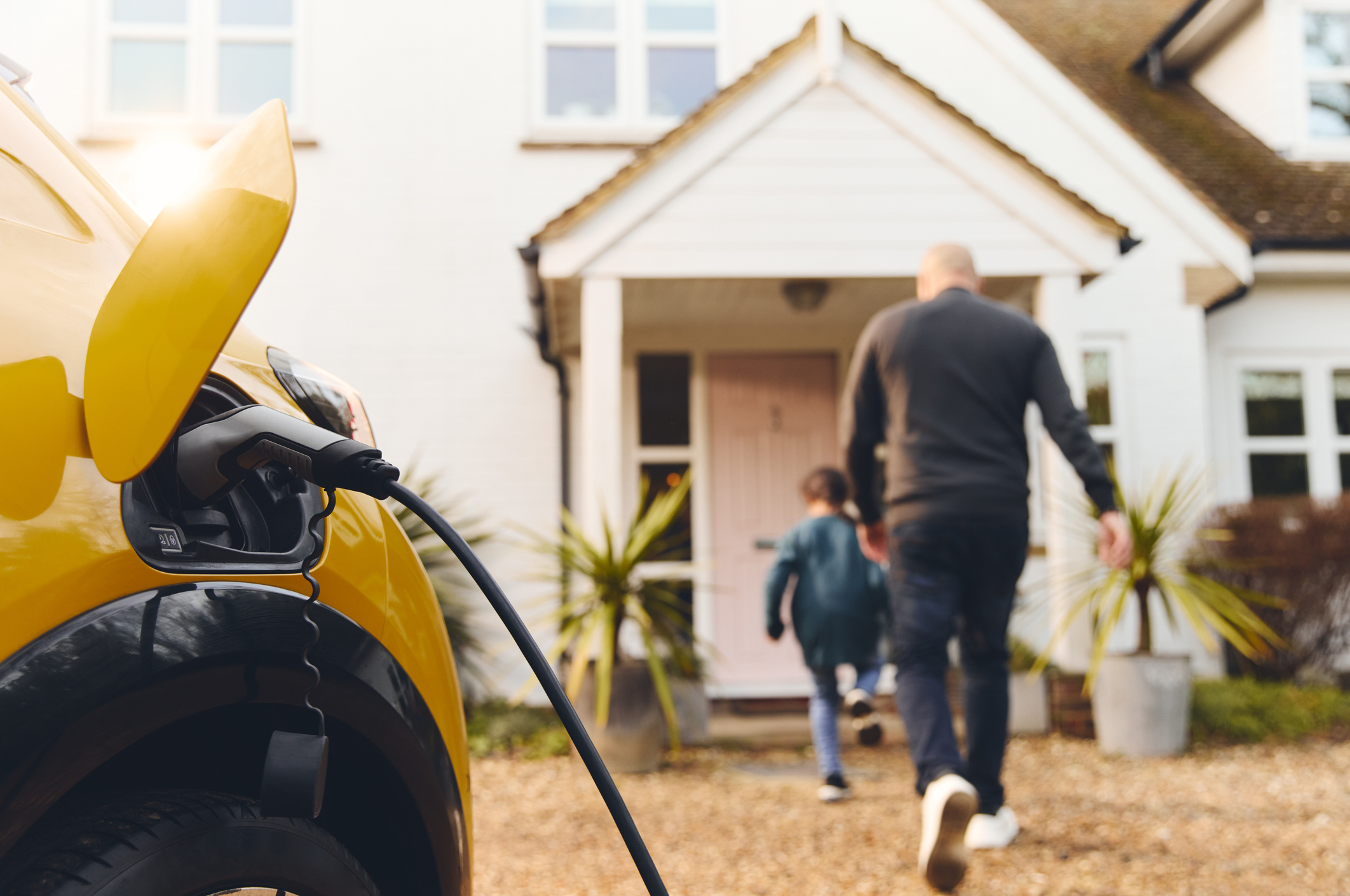 Electric car charging on driveway outside house