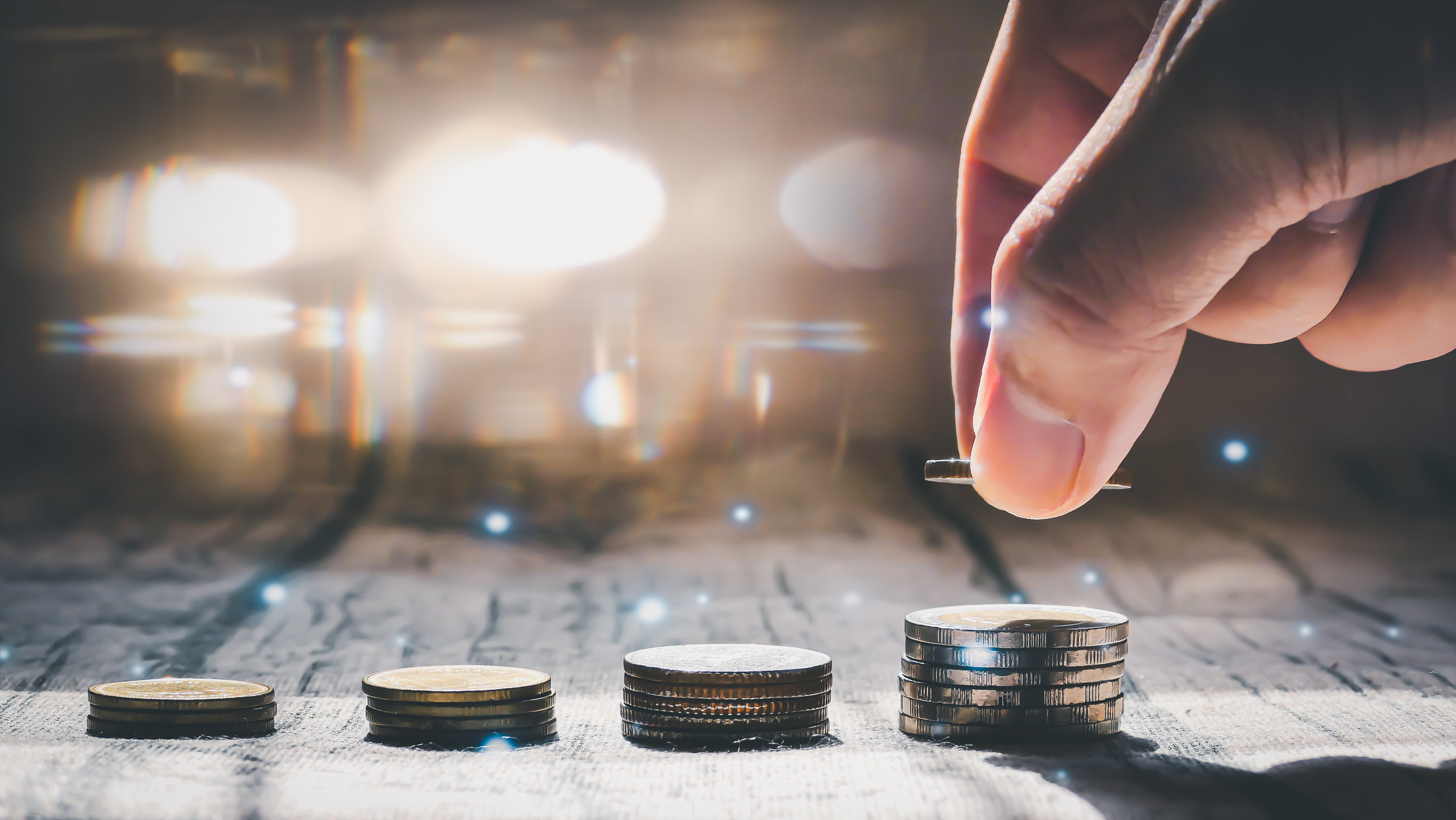 Man hand stacked coins with money saving concept and profit graph business finance in a piggy bank with money boxes for future funds of tourism, home, and retirement on a blurred background.