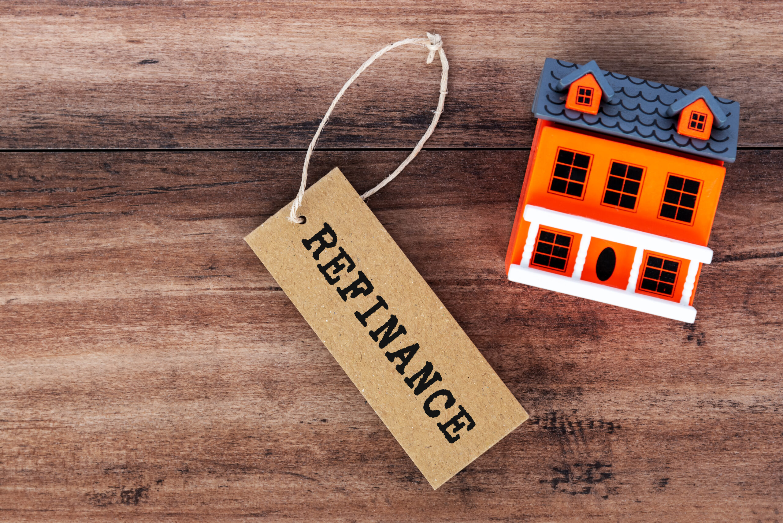 Refinance text on label tag with house model on wooden background
