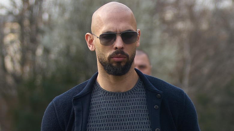 Andrew Tate walking outside court, wearing sunglasses