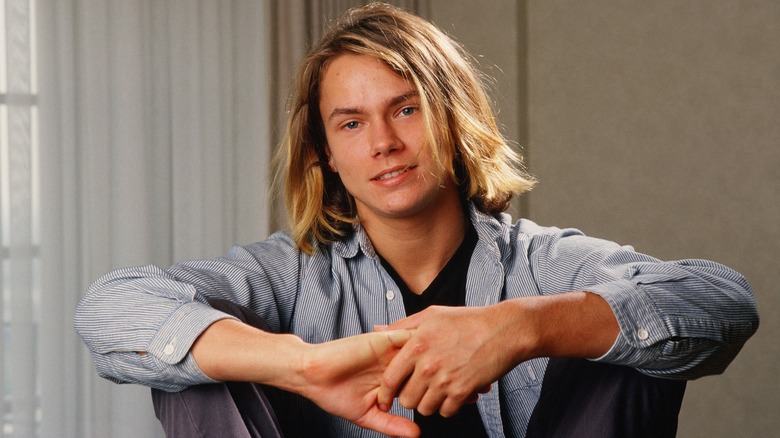 River Phoenix posing for a photo shoot with arms on knees