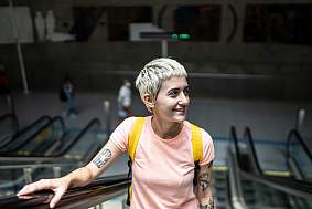 Young woman thoughtfully looking around while moving up on an escalator in a subway station.