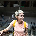 Young woman thoughtfully looking around while moving up on an escalator in a subway station.