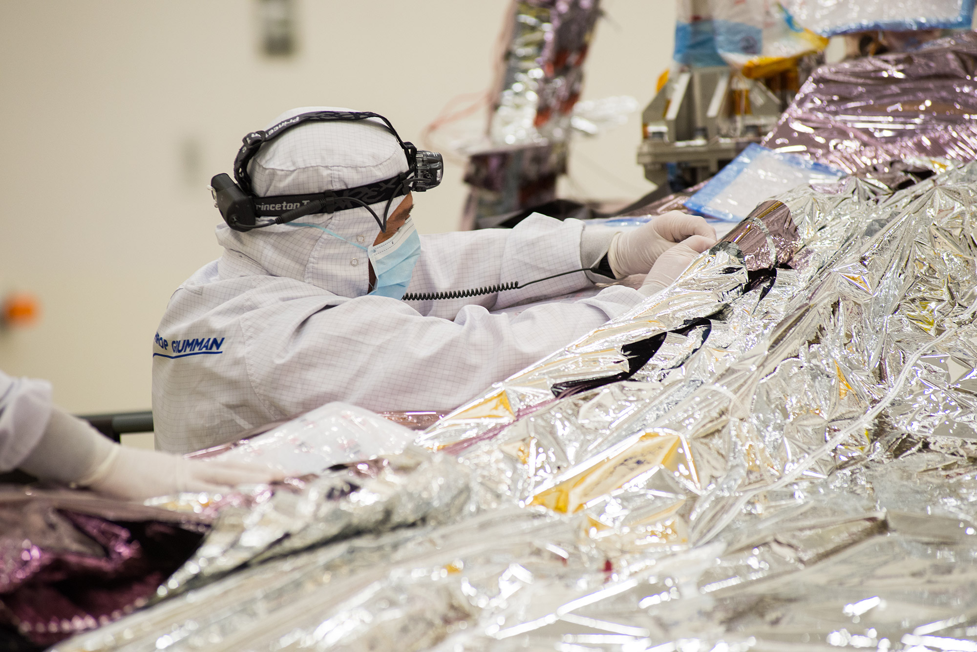 technician dressed in a bunny suit working on a telescope