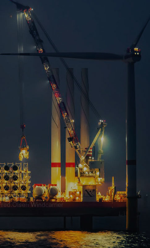 Heavy lift crane lifting pipline tanks at dusk