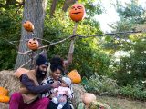 Family sitting on hay bales with pumpkins above them