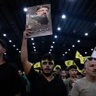 A supporter holds a poster of Hezbollah's top commander Fuad Shukr during a ceremony to mark the...