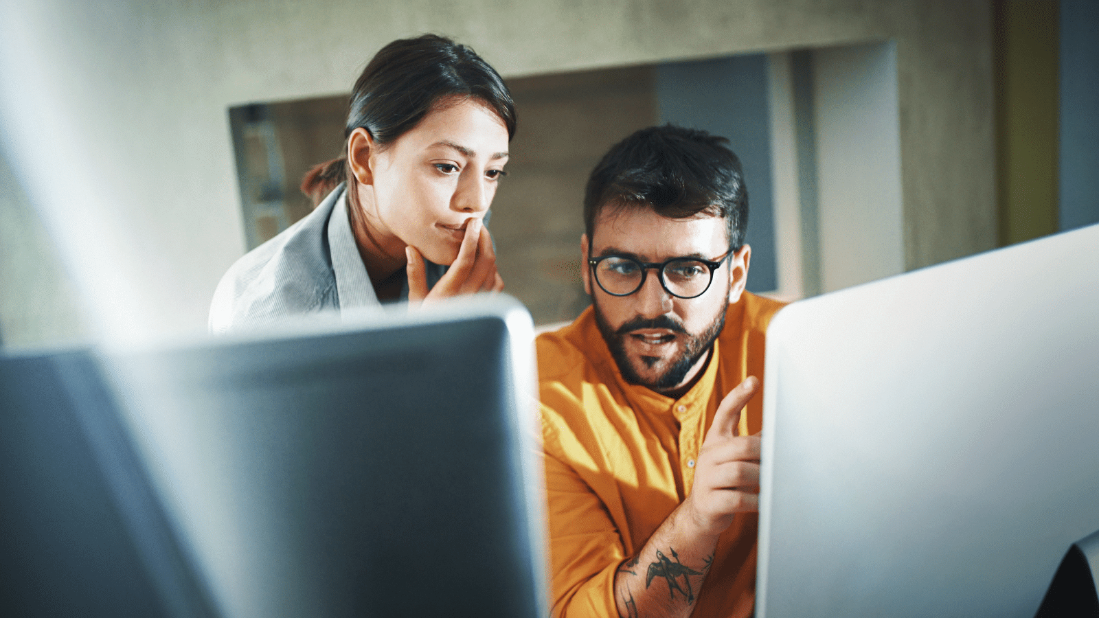 two people looking at computer screens, deliberating something