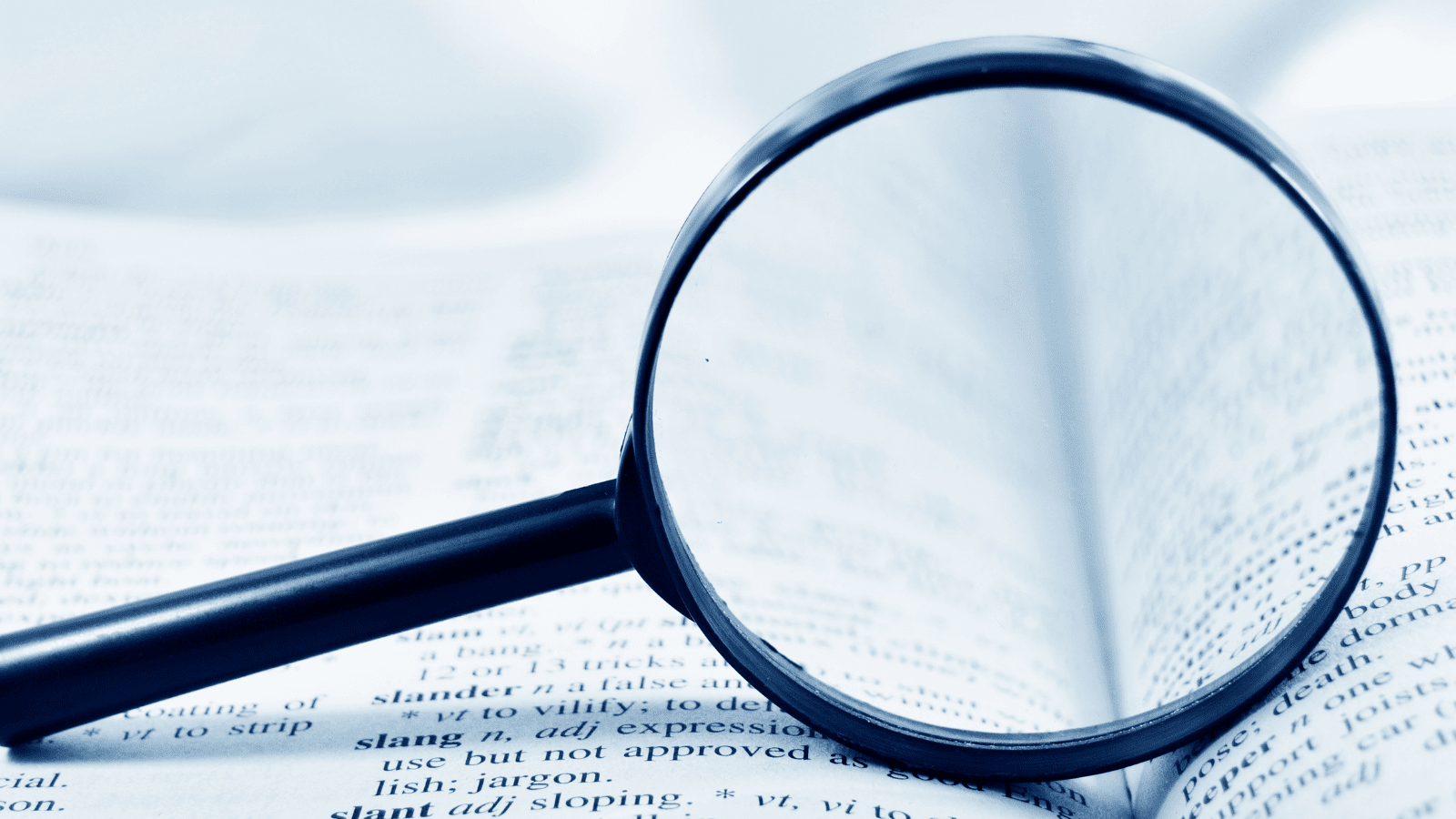 a large magnifying glass sits in between two pages of a dictionary