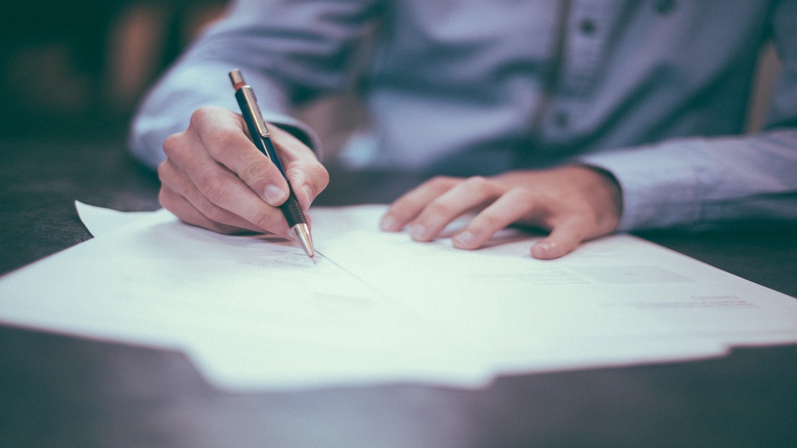 image of person looking over a few papers and checking something off with a pen.