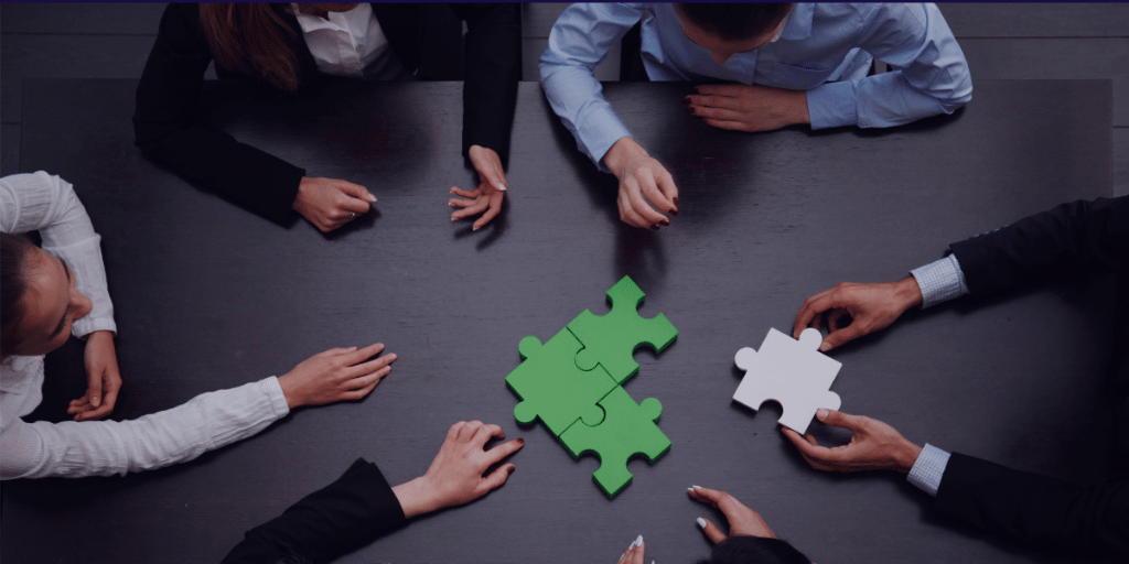 a team of people sitting down at a table solving a puzzle