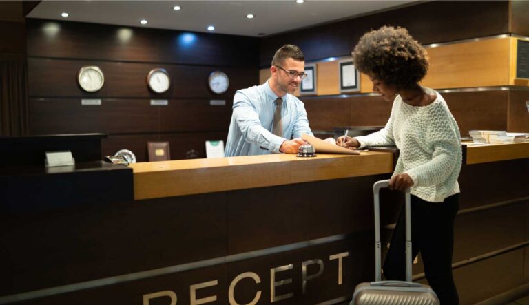 Image of male hotel receptionist checking in female hotel guest