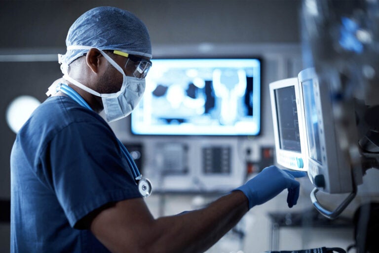 Image of medical professional working on touch screen of medical device.